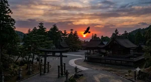 夕暮れ時の神社の境内と遥か上空の太陽に舞う一羽の巨大なカラスのシルエット